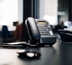 black ip desk phone on black wooden table