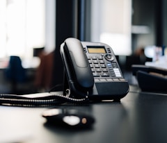 black ip desk phone on black wooden table