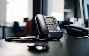 black ip desk phone on black wooden table