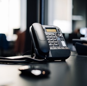 black ip desk phone on black wooden table