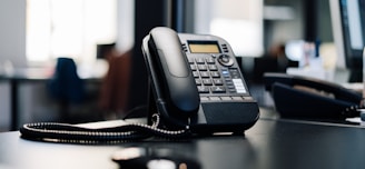 black ip desk phone on black wooden table