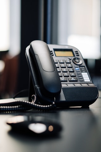 black ip desk phone on black wooden table