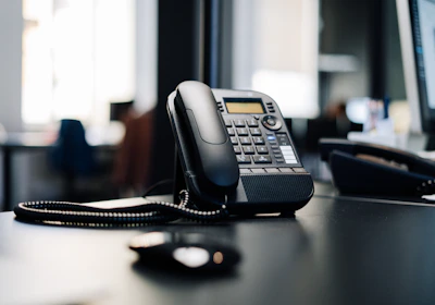 black ip desk phone on black wooden table