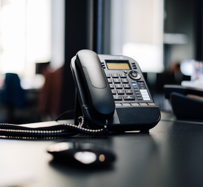 black ip desk phone on black wooden table