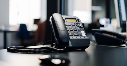 black ip desk phone on black wooden table