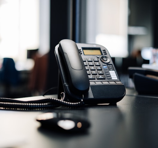 black ip desk phone on black wooden table