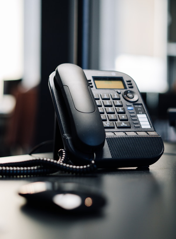 black ip desk phone on black wooden table