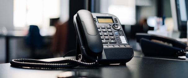 black ip desk phone on black wooden table