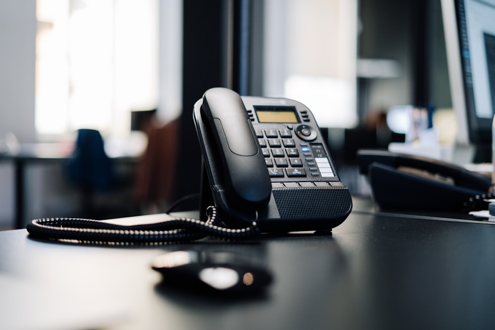 téléphone de bureau IP noir sur table en bois noir