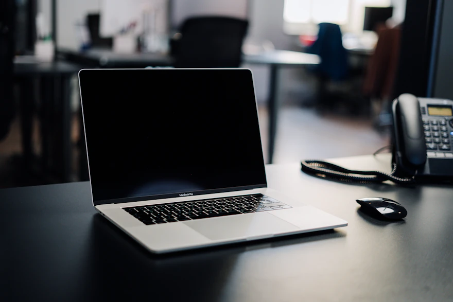An office desk phone and laptop set up for handling patient scheduling calls