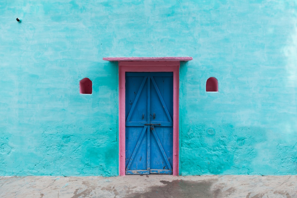red wooden door on blue concrete wall