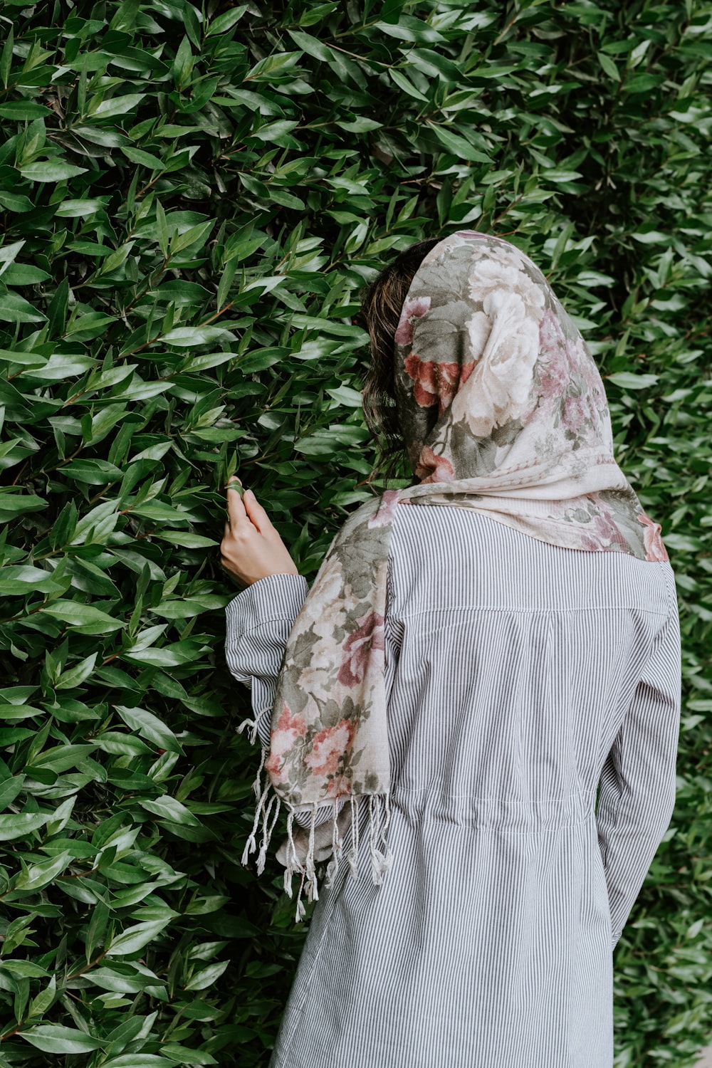 woman in white and red hijab standing near green plants