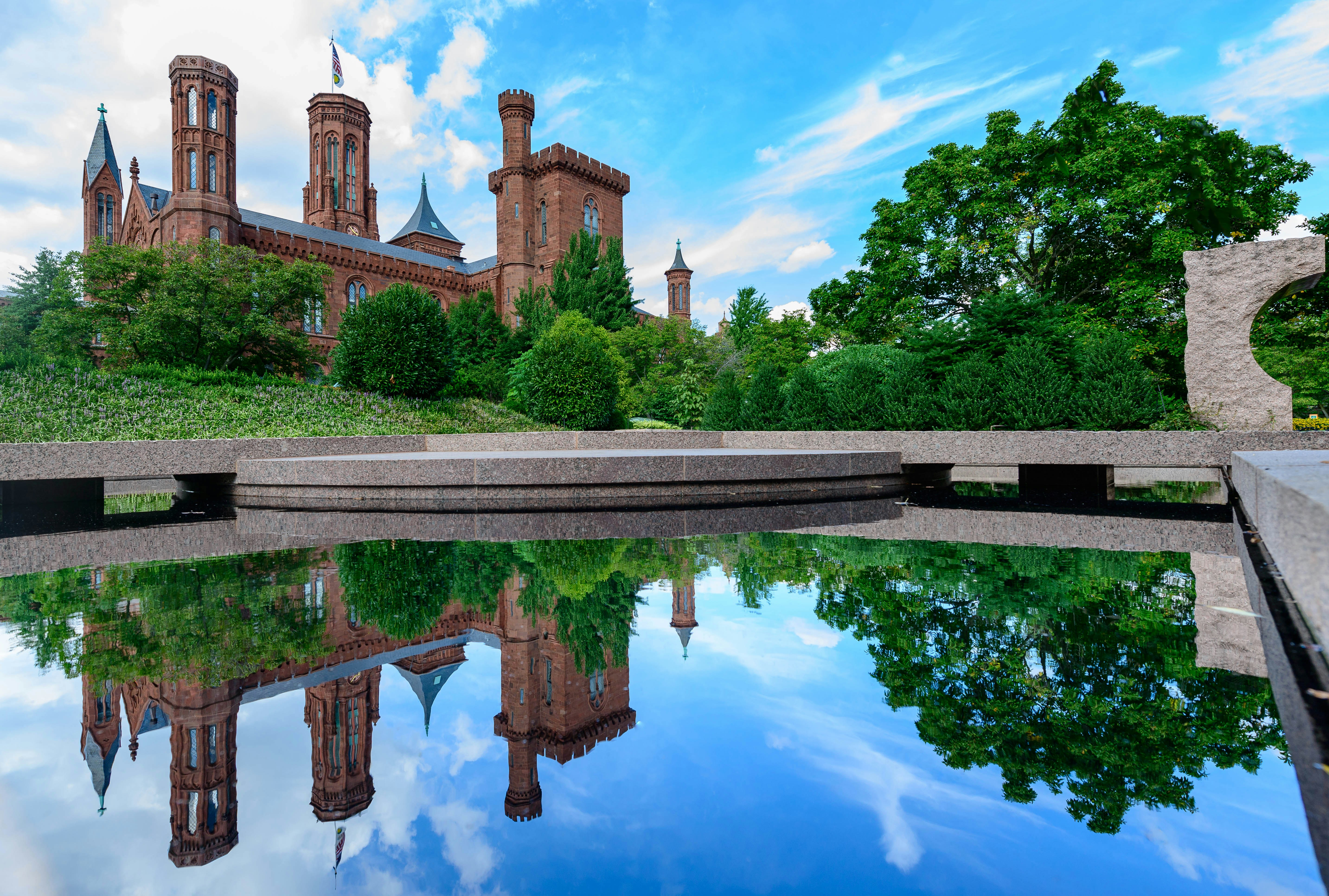 brown concrete building near green trees and body of water during daytime
