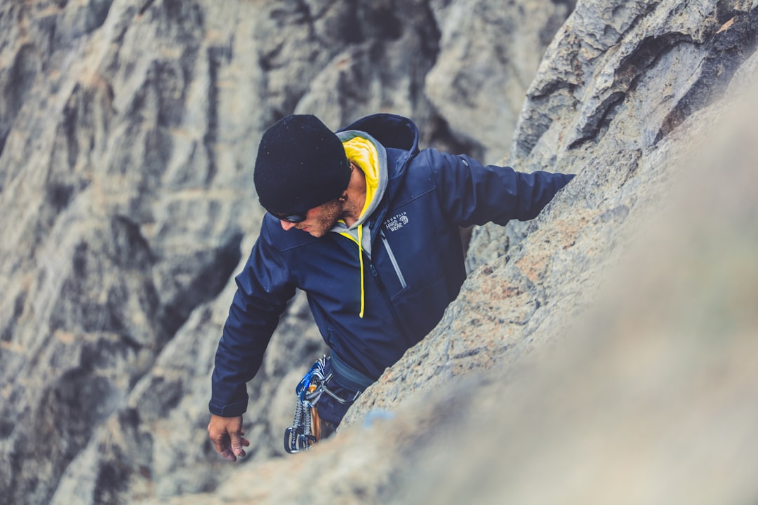man in blue jacket climbing on rocky mountain during daytime
