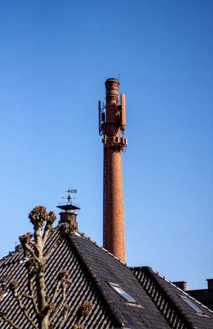 A friendly technician in uniform inspecting a chimney on a sunny San Francisco rooftop.