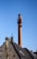 A technician inspecting a chimney with tools in hand, surrounded by a clean residential outdoor setting.