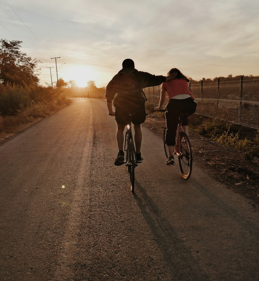 man in black jacket riding bicycle on road during sunset