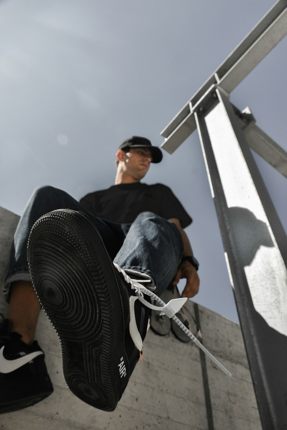 man in black shirt and blue denim jeans wearing black sunglasses sitting on white metal frame