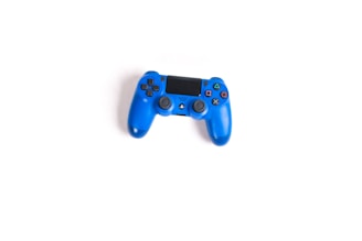 A blue gaming controller with black buttons and a central touchpad, placed against a white background.