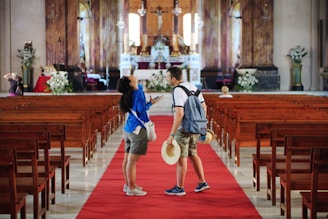 man in blue shirt and white shorts carrying white hat walking on red carpet