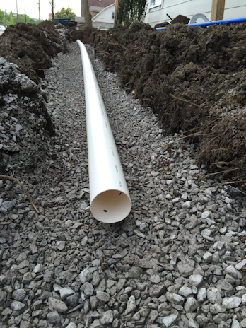 A close-up of a freshly installed septic tank surrounded by gravel and soil.