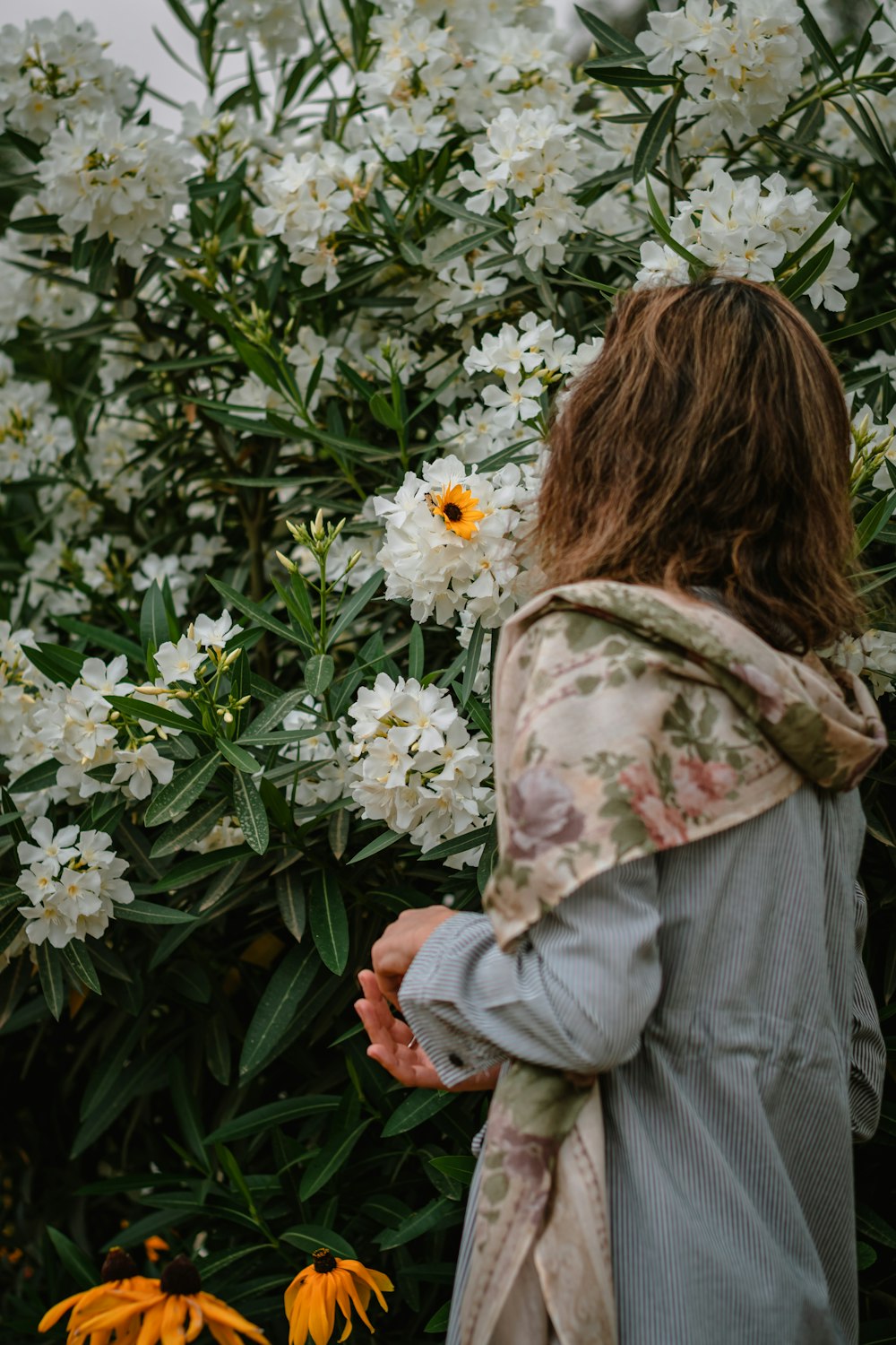 woman in gray jacket holding white flowers