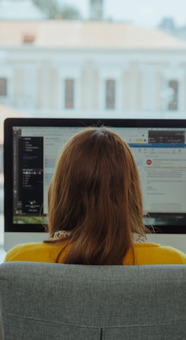 woman in yellow shirt sitting on chair in front of computer