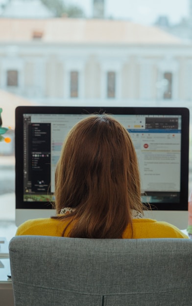 woman in yellow shirt sitting on chair in front of computer