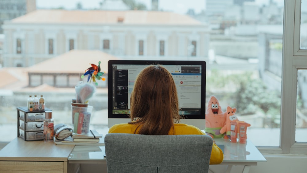 woman in yellow shirt sitting on chair in front of computer