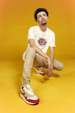 man in white crew neck t-shirt and brown pants sitting on yellow floor