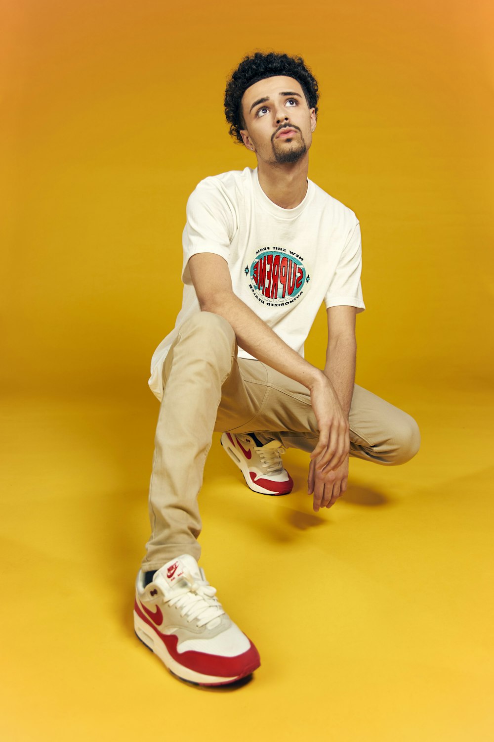 man in white crew neck t-shirt and brown pants sitting on yellow floor