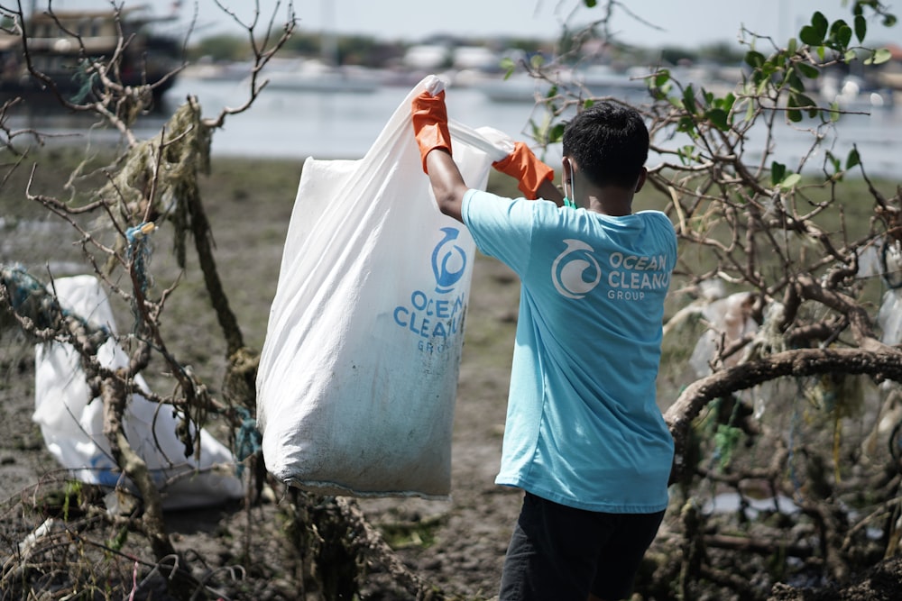 man in blue t-shirt holding white plastic bag