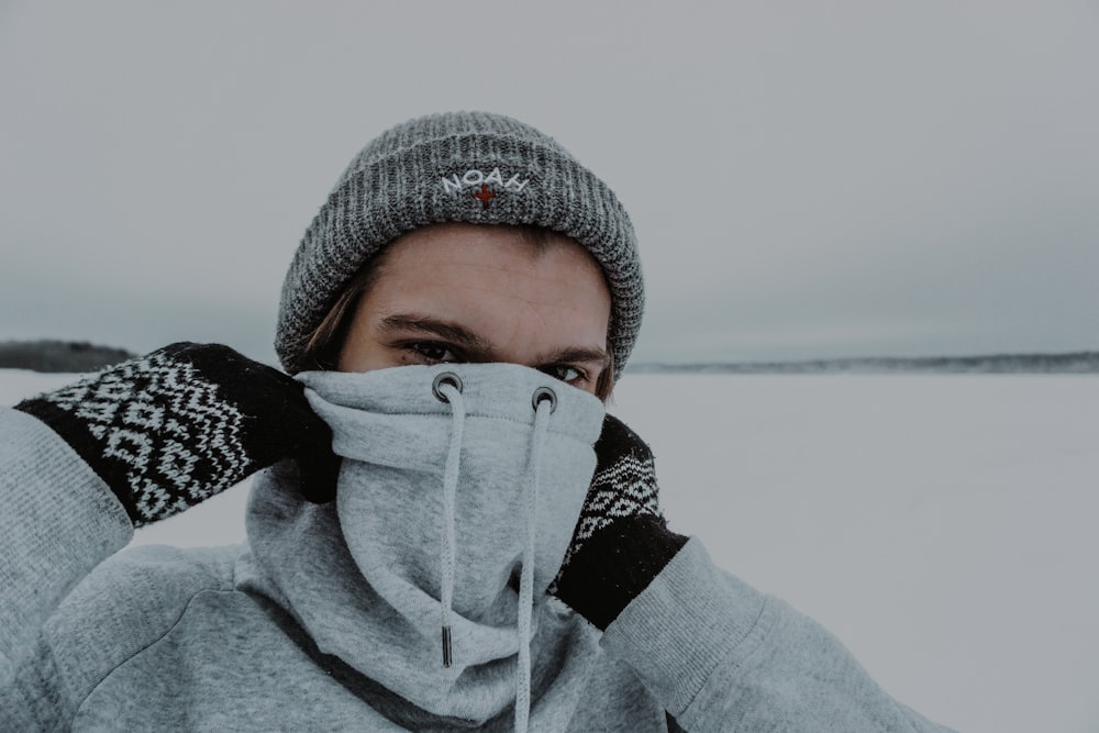 woman in gray knit cap covering her face with gray knit cap