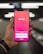 A hand holding a smartphone displaying the Tinder app login screen, with options to log in using Google or a phone number. The background is blurred, suggesting a dynamic setting, possibly a moving walkway or escalator.