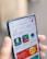 A hand is holding a smartphone displaying an app store interface. The screen shows recently updated apps with icons and ratings. The top bar includes a search function and navigation tabs.