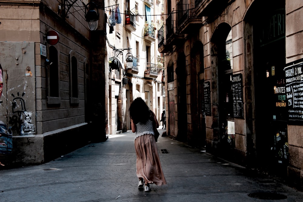 woman in red dress walking on sidewalk during daytime