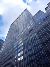 A panoramic view of a recently completed commercial tower featuring shimmering glass and aluminium cladding under a clear sky.