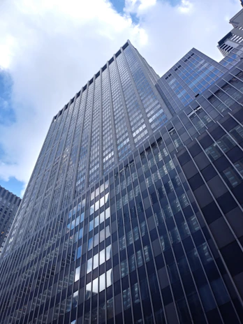 A panoramic view of a recently completed commercial tower featuring shimmering glass and aluminium cladding under a clear sky.