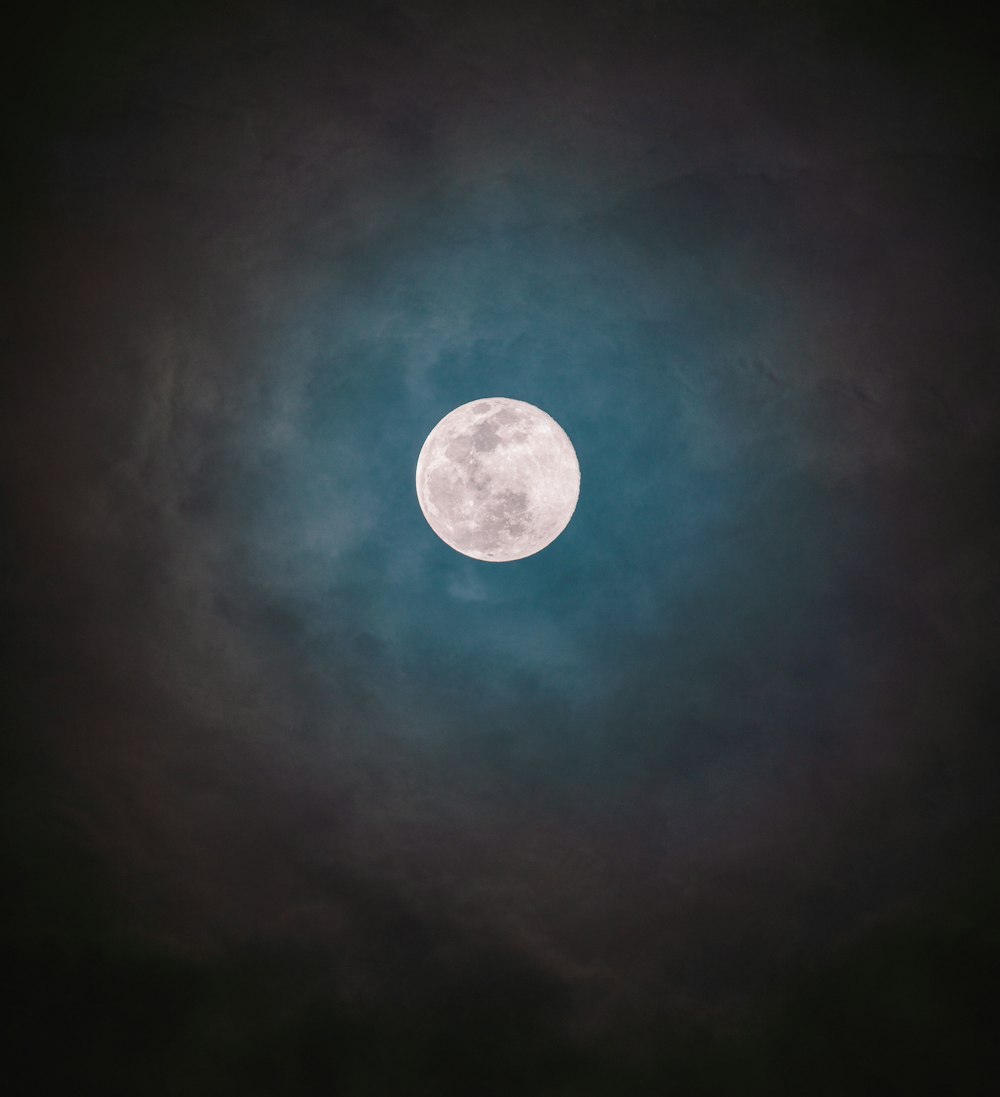 a full moon seen through a cloudy sky