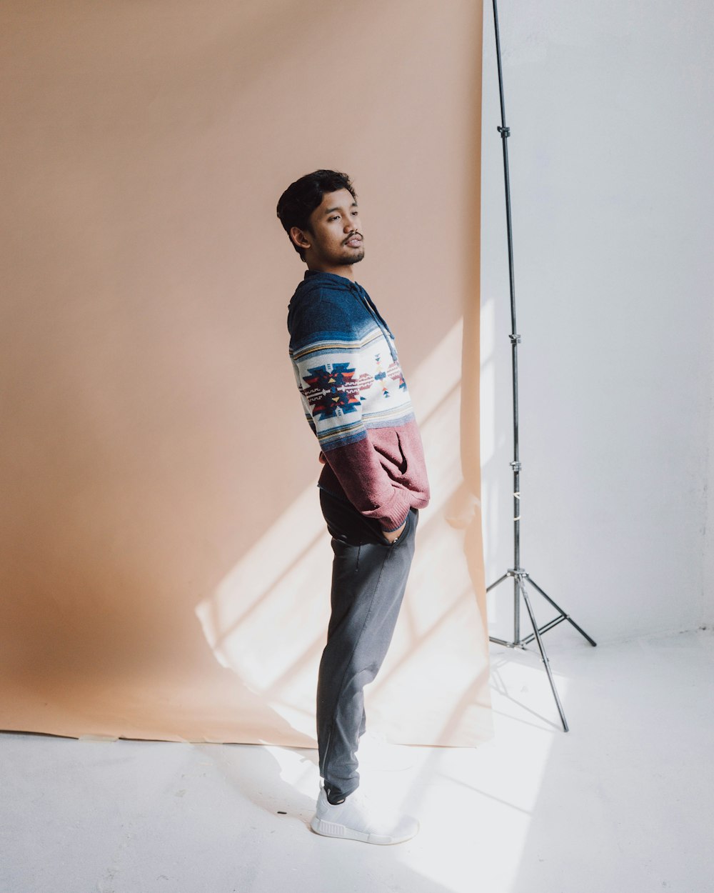 boy in blue and orange striped shirt and blue denim jeans standing beside white wall