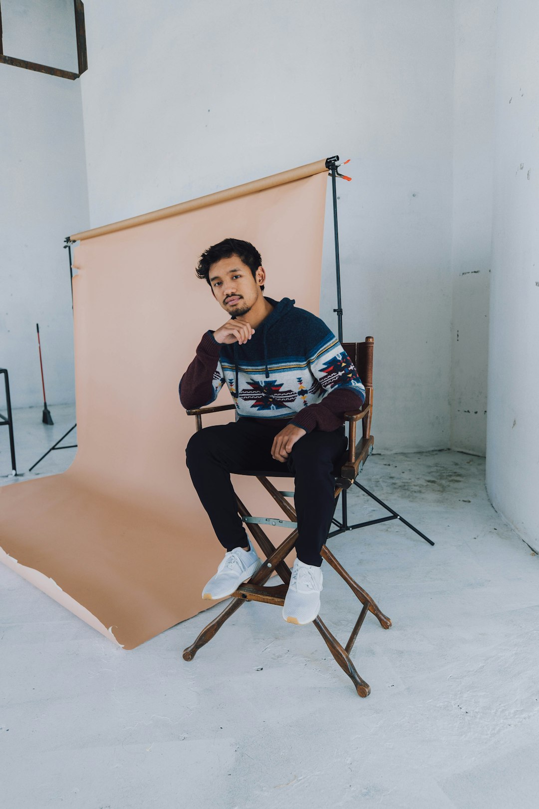 man in blue and white crew neck t-shirt sitting on brown wooden chair