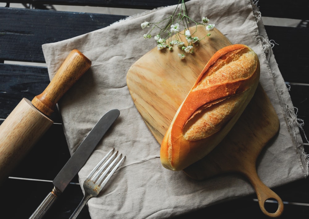 sliced bread on brown wooden chopping board beside silver fork