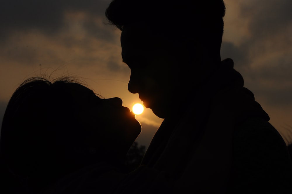 silhouette of man and woman kissing during sunset