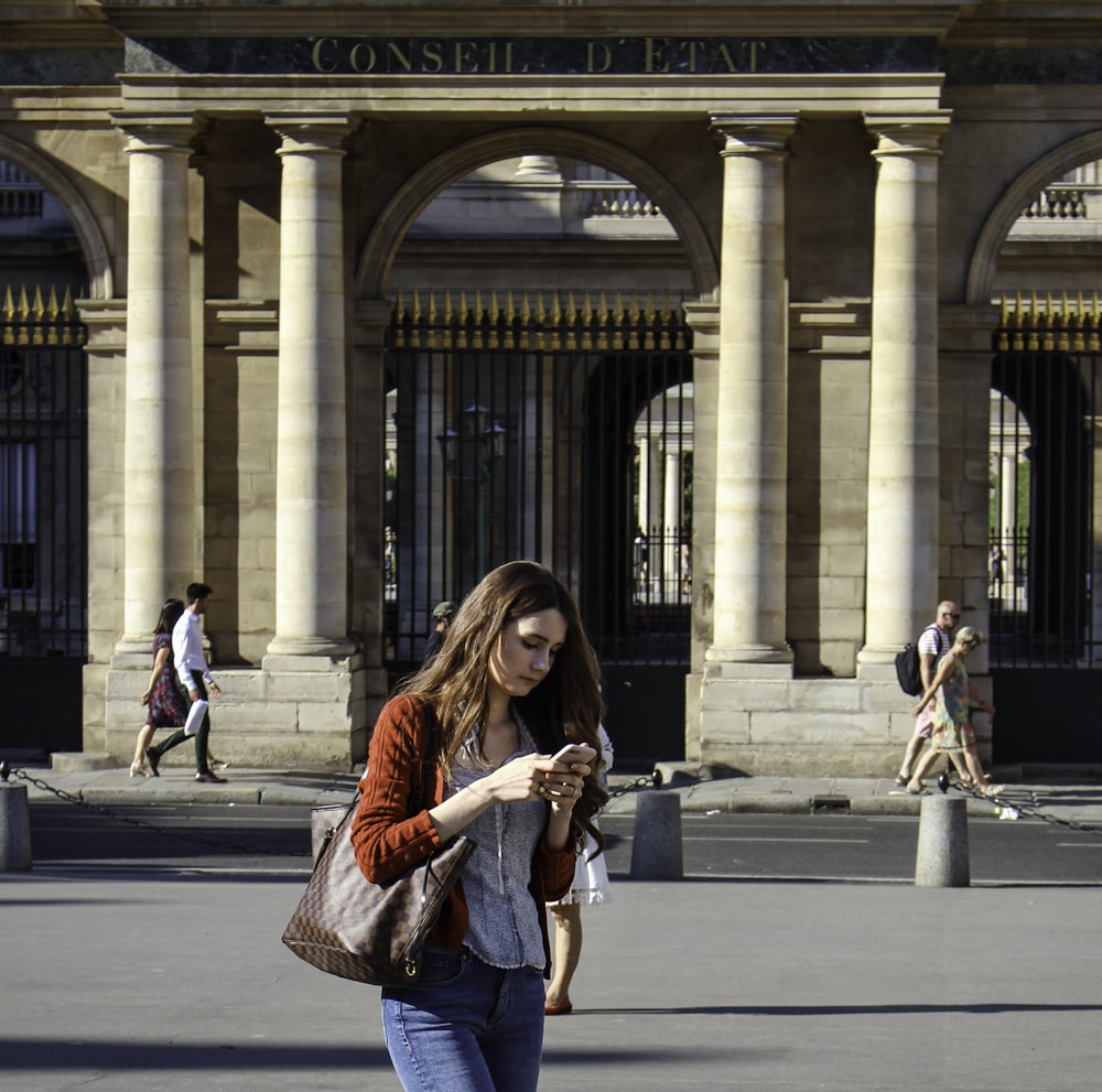 woman in red and black long sleeve shirt standing on sidewalk during daytime