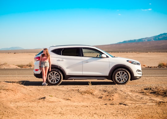 woman in blue denim jacket standing beside silver 5 door hatchback during daytime in Death Valley National Park United States