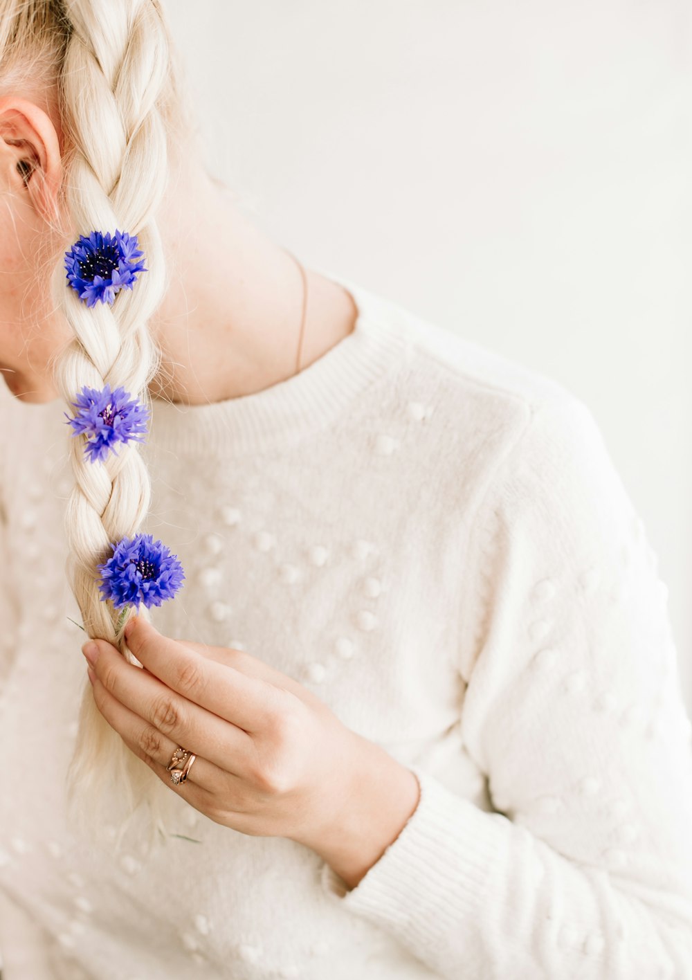 woman in white long sleeve shirt holding blue flower