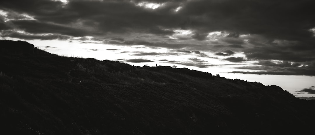 grayscale photo of mountain under cloudy sky