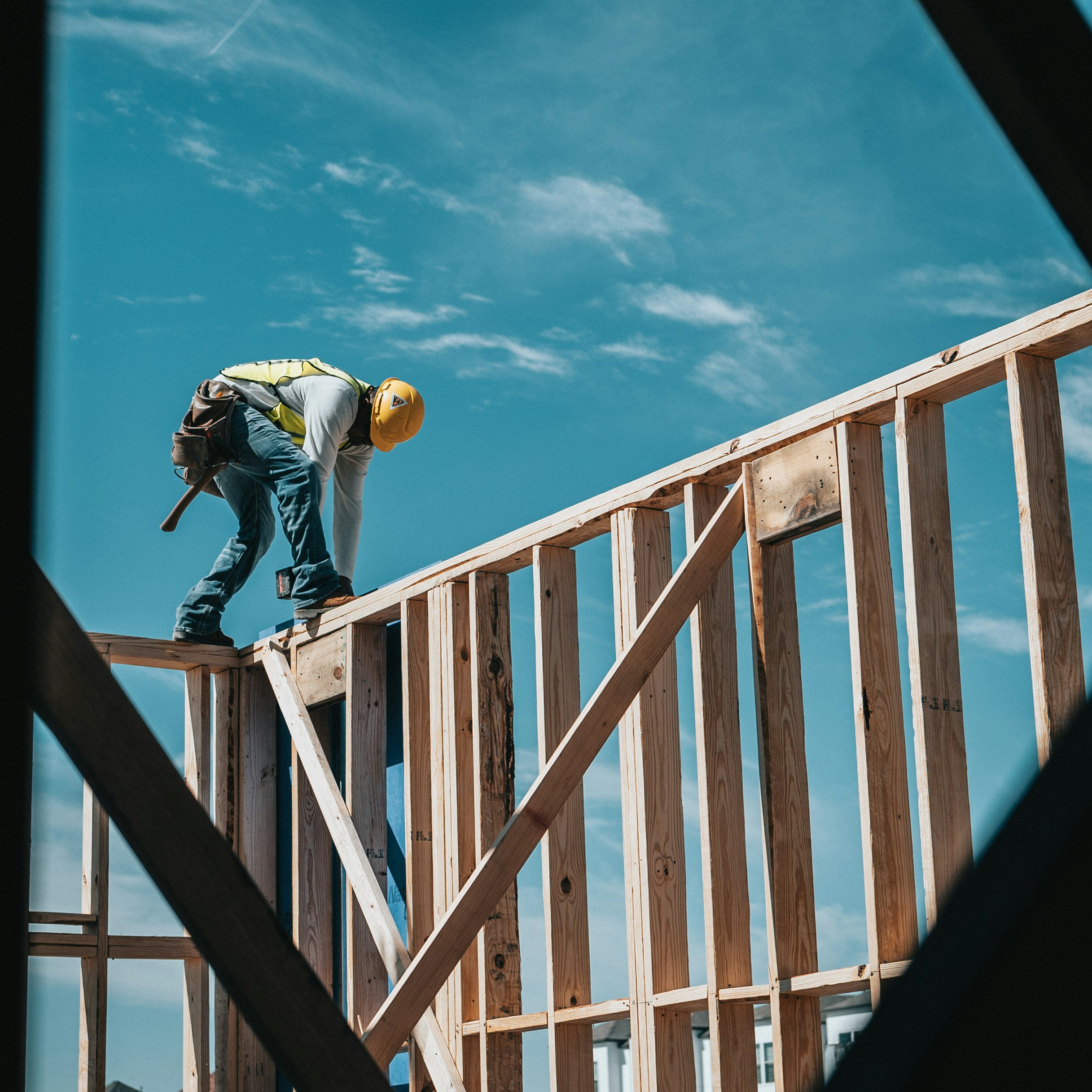 man in yellow shirt and blue denim jeans jumping on brown wooden railings under blue and