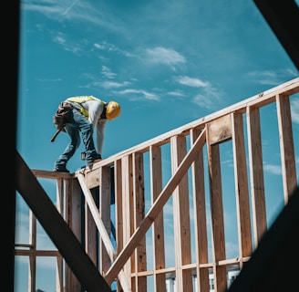 man in yellow shirt and blue denim jeans jumping on brown wooden railings under blue and