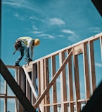 man in yellow shirt and blue denim jeans jumping on brown wooden railings under blue and